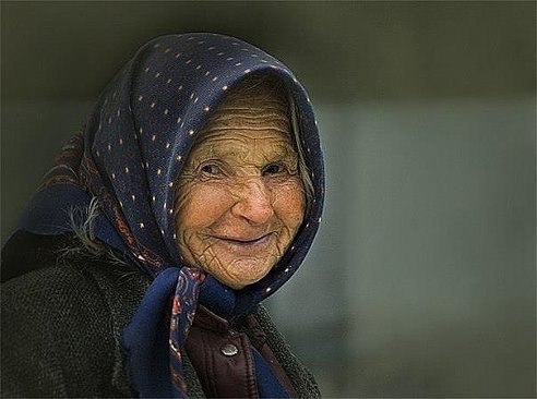 На пляже семья купалась и строила замки из песка. Возле них крутилась старушка, седые волосы, рваная ...