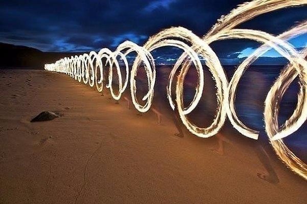 Фотография бегущего с огнем человека на длинной выдержке.